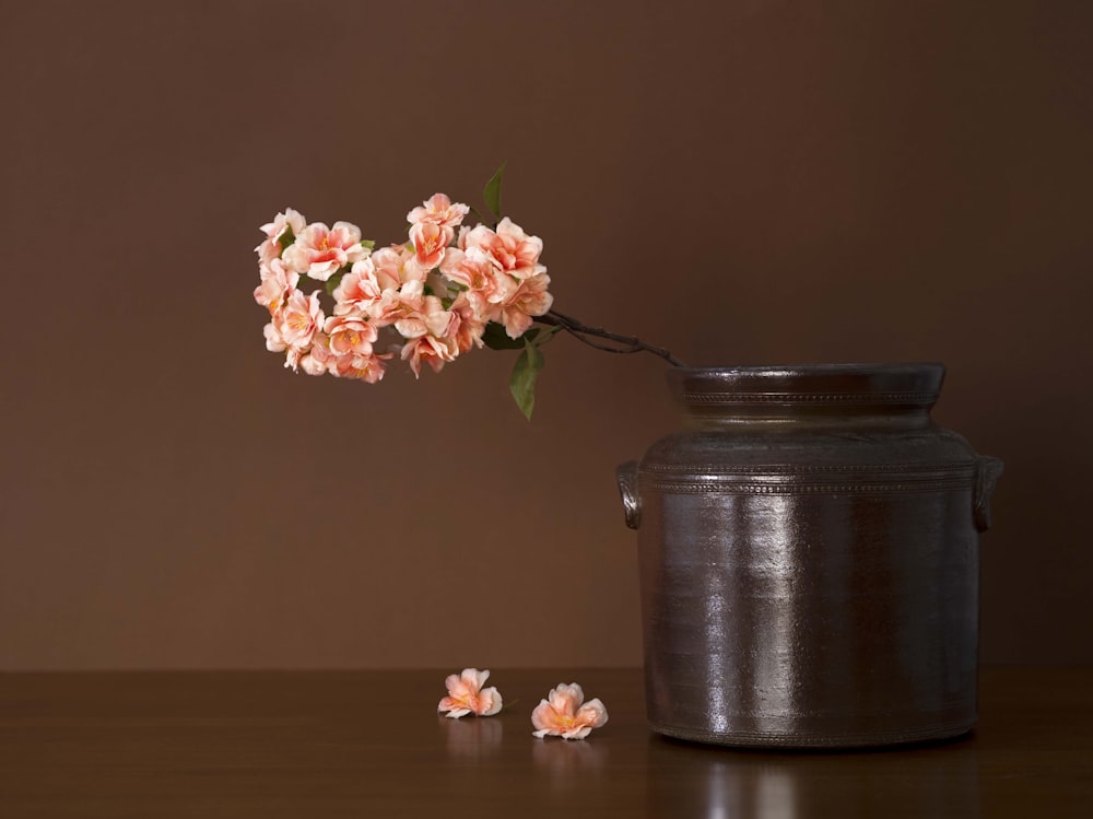 a vase filled with pink flowers next to a metal container