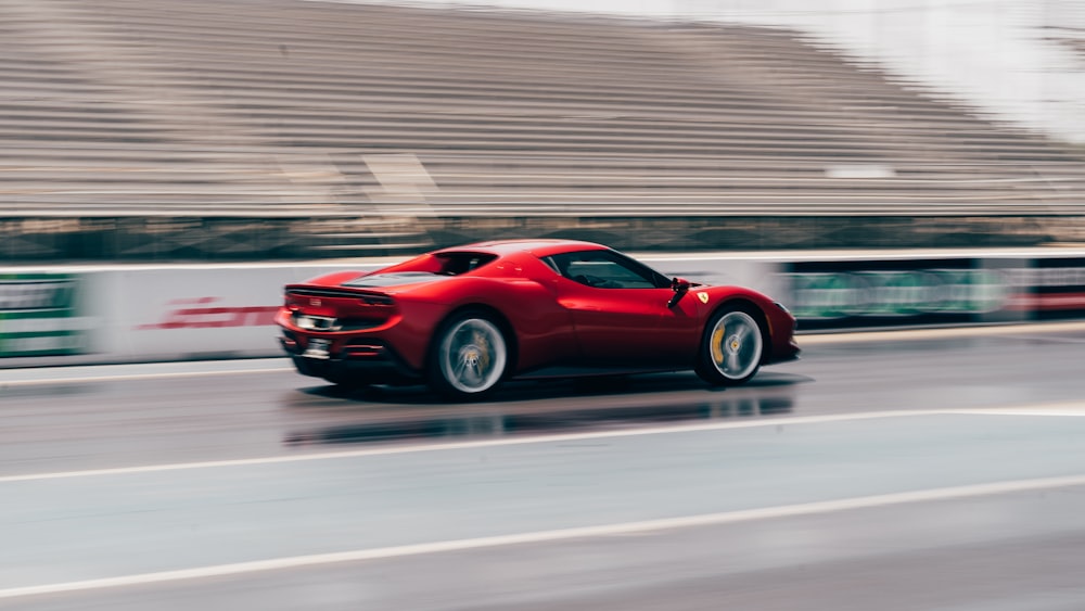 a red sports car driving down a wet road