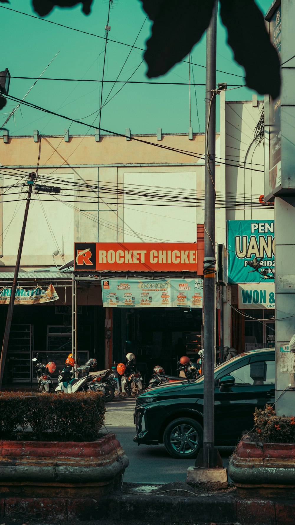 a street corner with cars and motorcycles parked on the side of the road