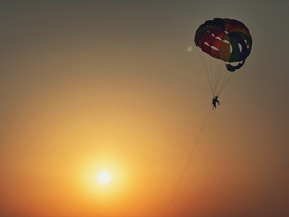 a person is parasailing over the ocean at sunset