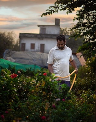 A technician adjusting irrigation equipment in a lush home garden.