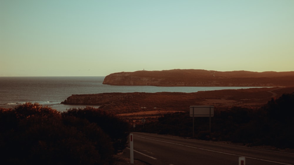 a road next to a body of water at sunset