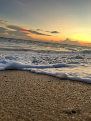 Gentle waves caressing a sandy shore under a pastel sunset sky.
