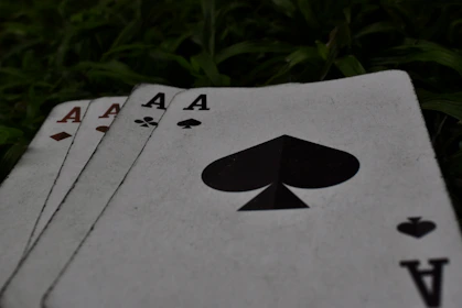 four playing cards sitting on the ground in the grass