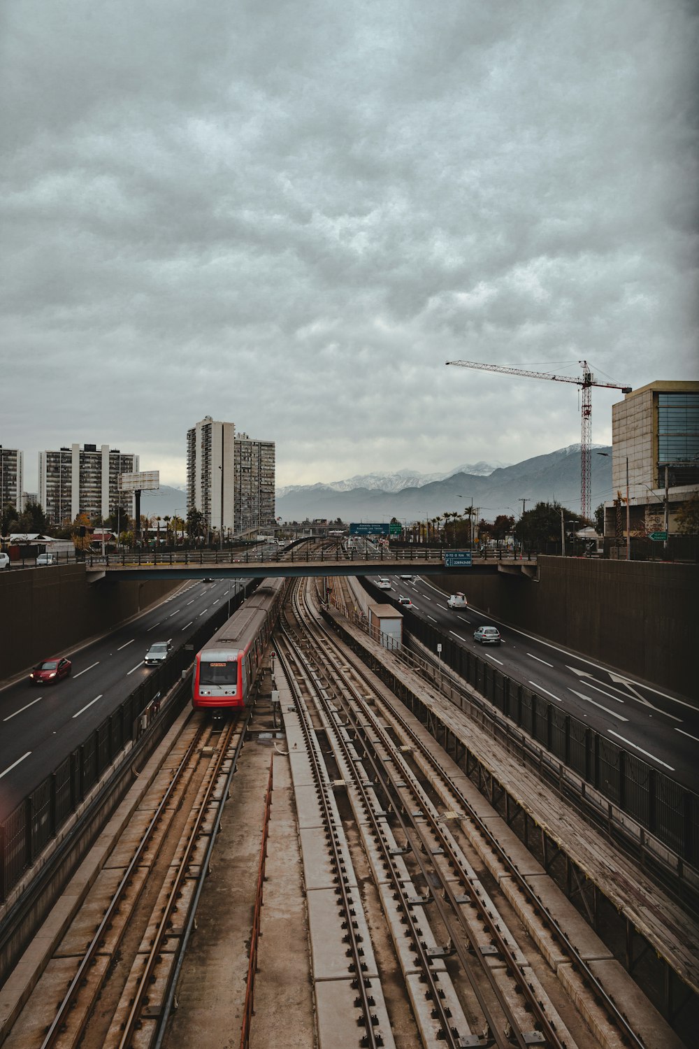 a red train traveling down train tracks next to tall buildings