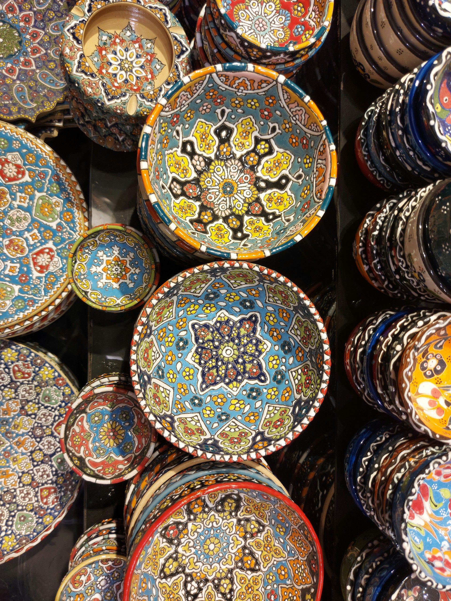 A close-up of colorful hand-painted ceramic bowls arranged on a wooden table, showcasing delicate brush strokes and vibrant patterns.