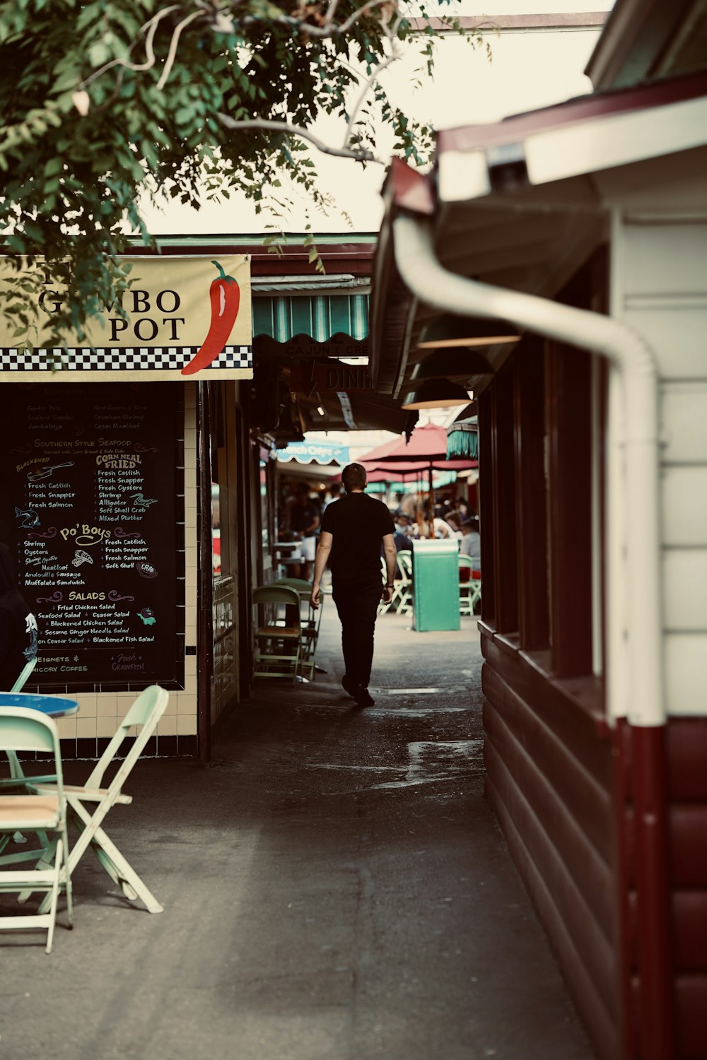 um homem caminhando por uma rua ao lado de um restaurante