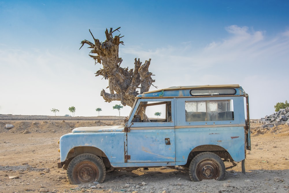 an old blue truck parked in the desert