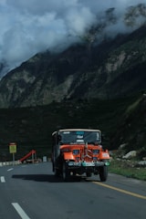 a jeep driving down a road with mountains in the background