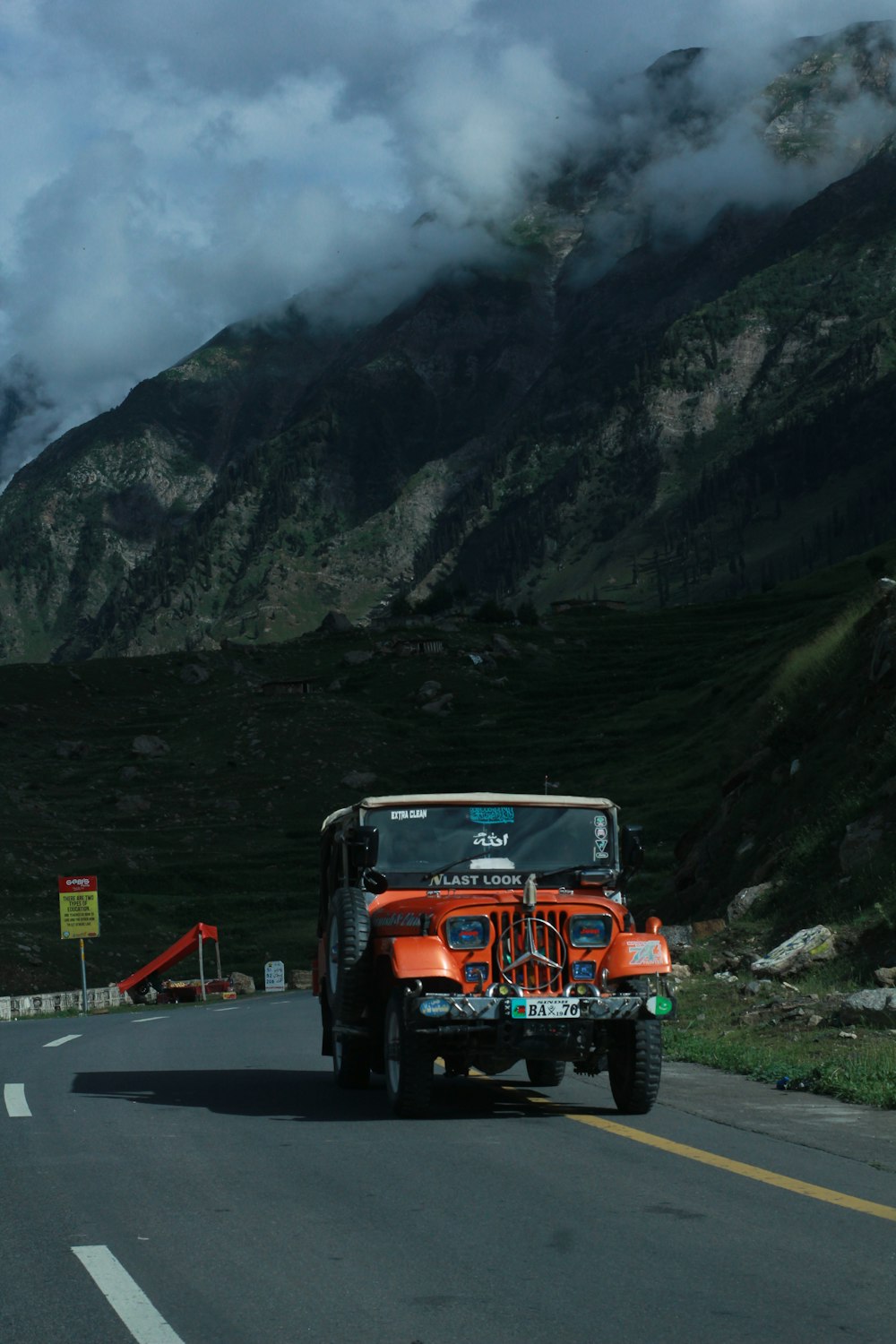 a jeep driving down a road with mountains in the background