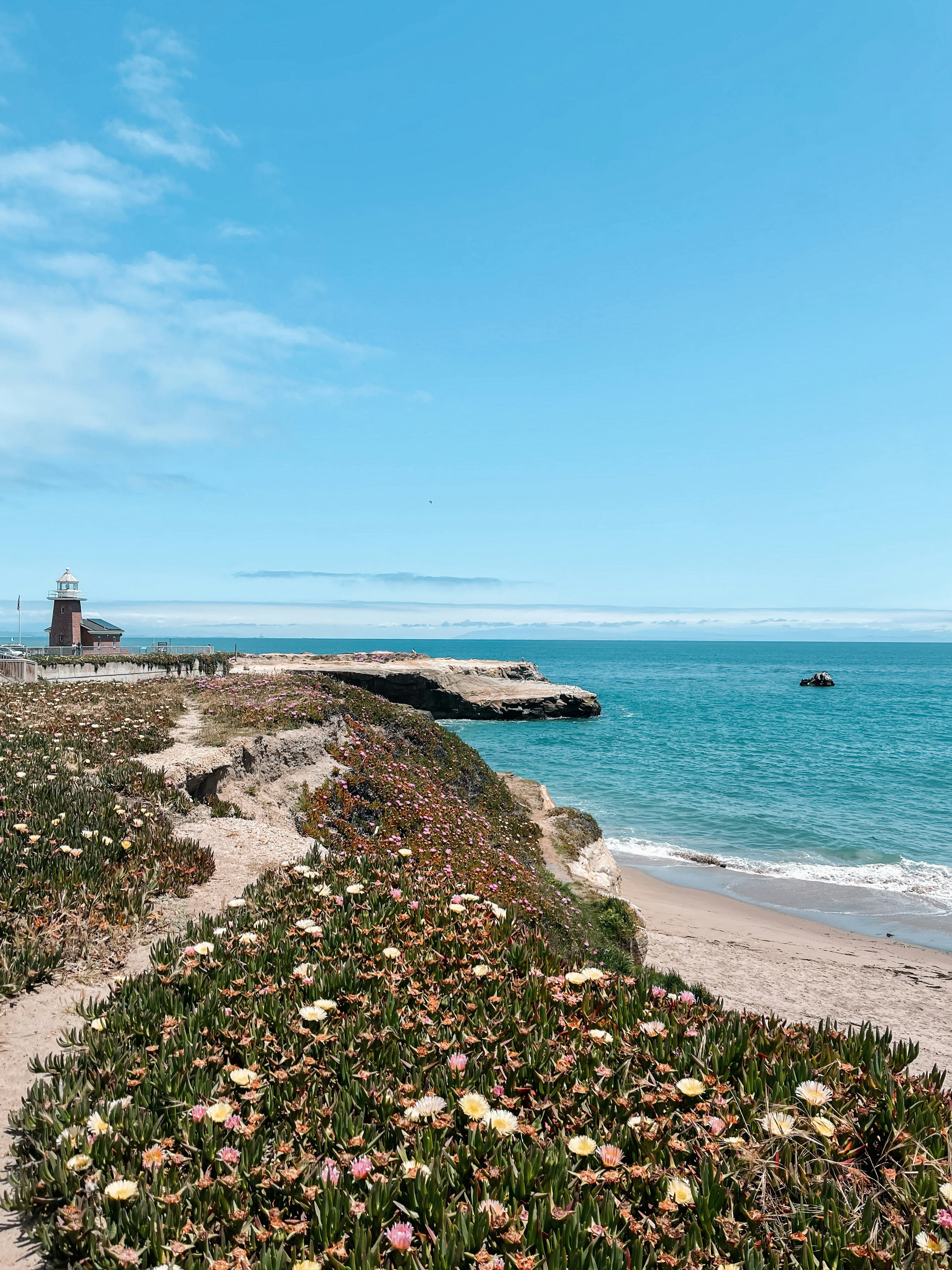 Una spiaggia di sabbia con un faro in lontananza