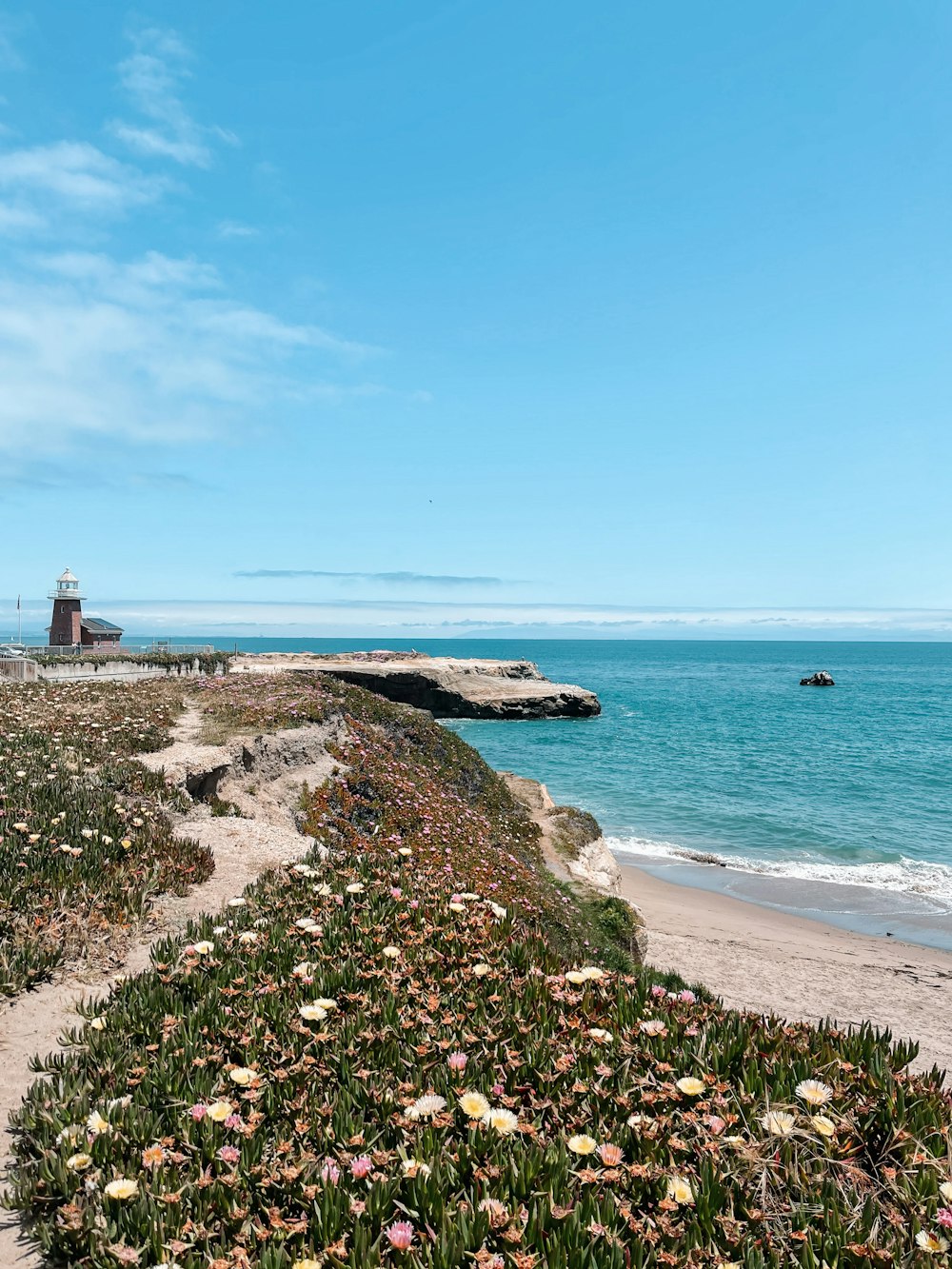 a sandy beach with a lighthouse in the distance