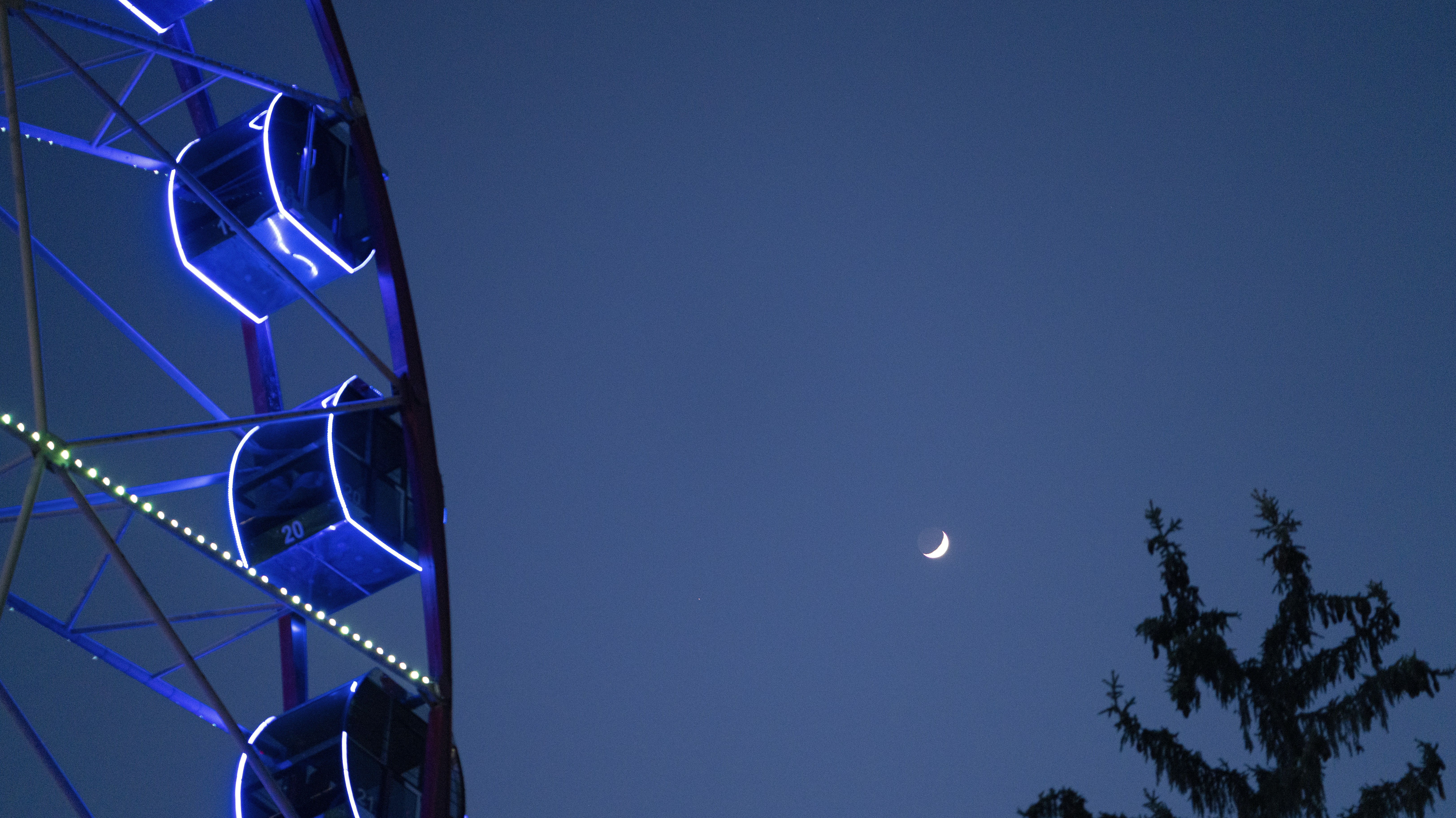 a ferris wheel with a half moon in the sky