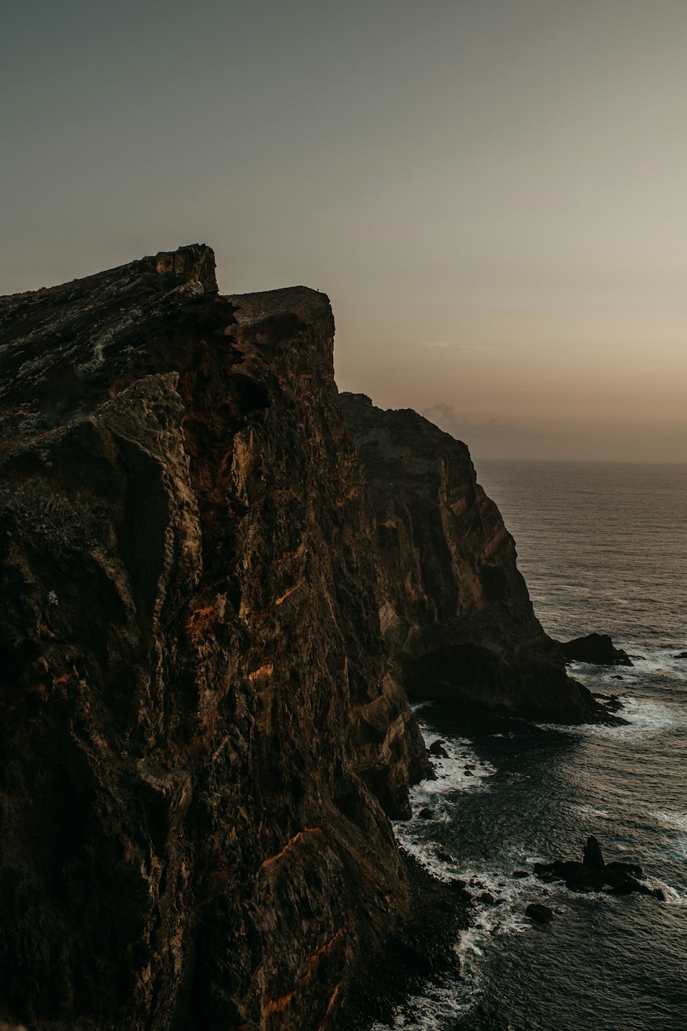 a rocky cliff with a body of water in the background