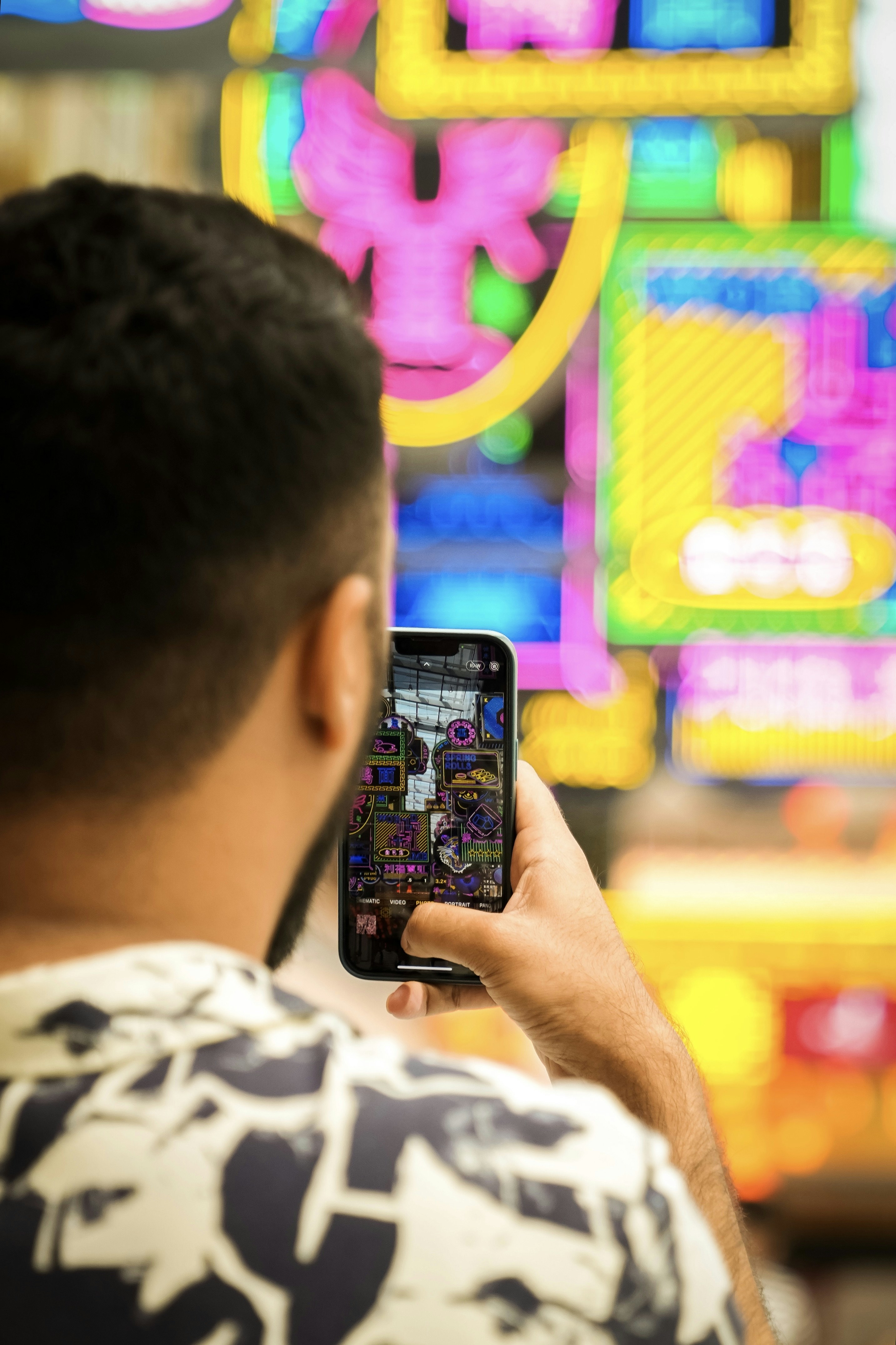 a man holding a cell phone in front of neon signs