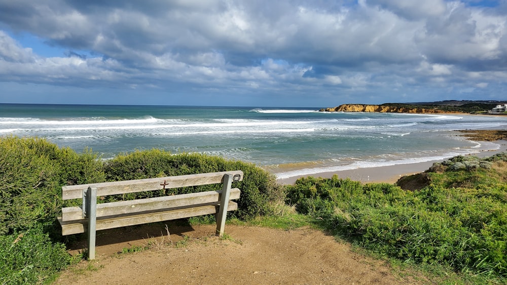 a wooden bench sitting on top of a sandy beach