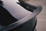 Close-up of a sleek black ABS car spoiler installed on a sporty vehicle