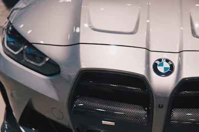 Front view of a BMW M series with aerodynamic hood vents and a widebody kit in an industrial backdrop.