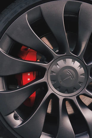 Close-up of red brake calipers gripping a matte black wheel with sharp focus.