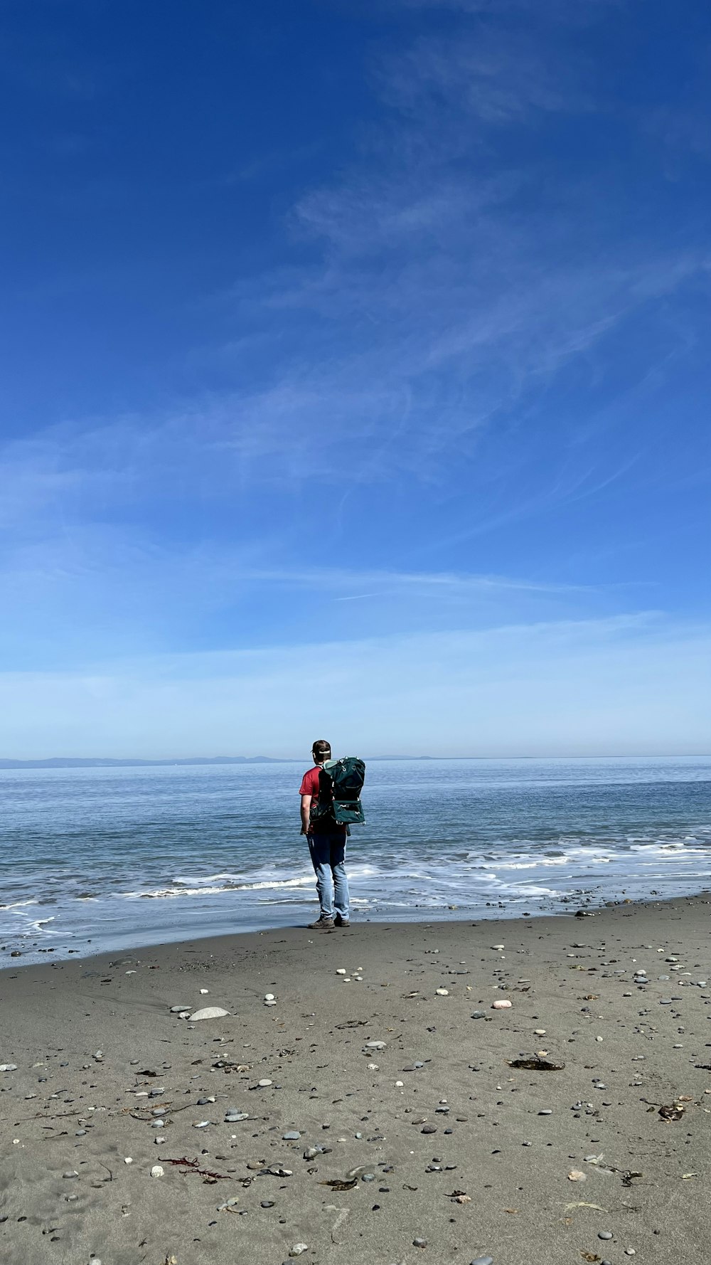 a man with a backpack walking on the beach