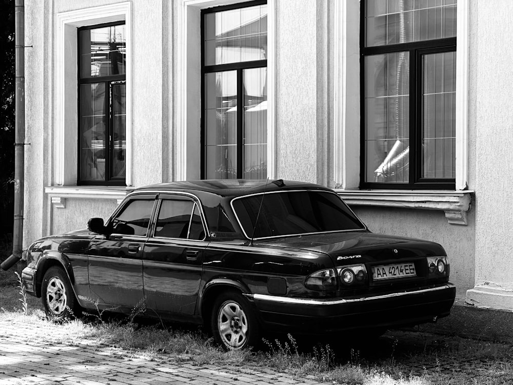 une photo en noir et blanc d’une voiture garée devant un immeuble