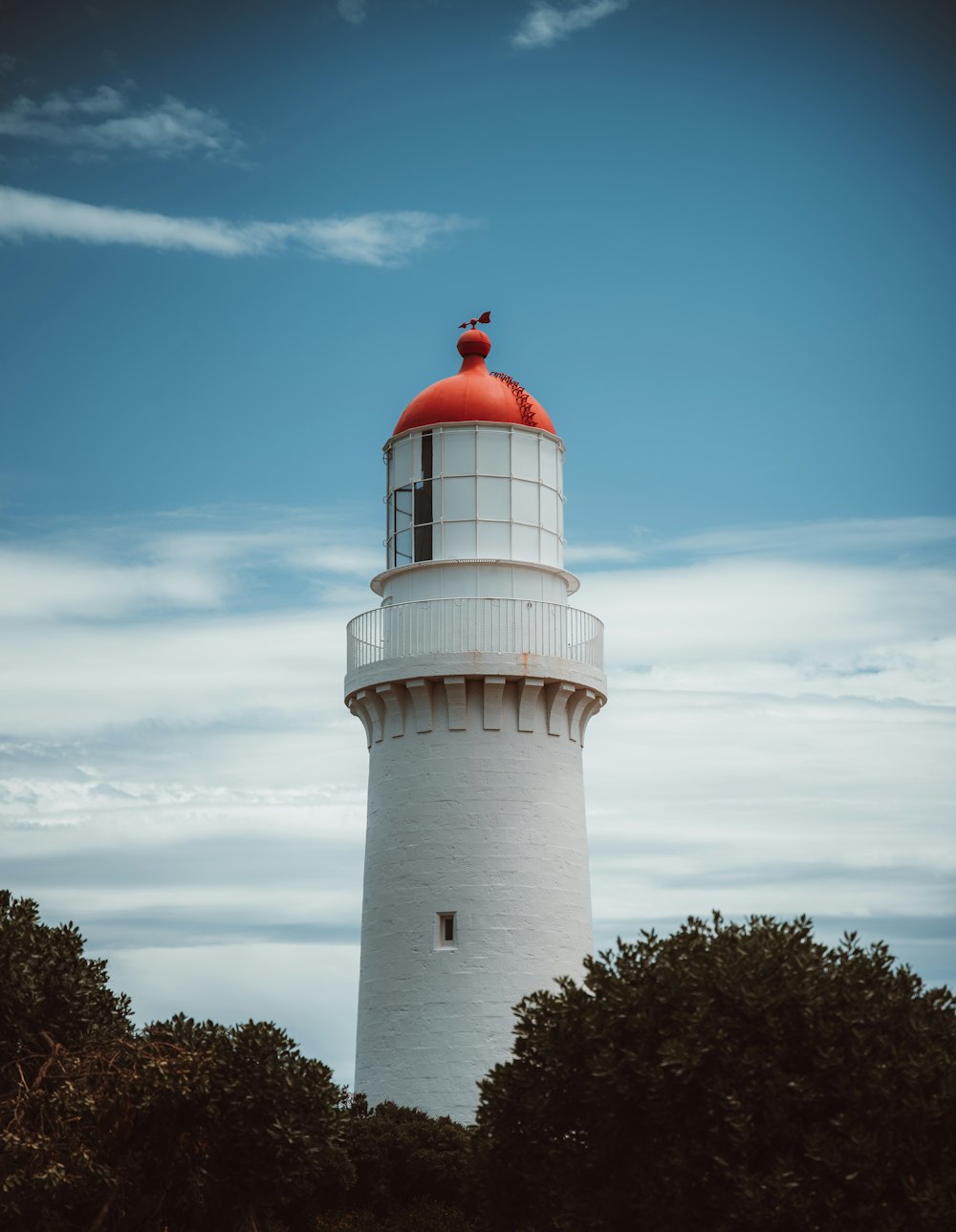 a white and red lighthouse surrounded by trees