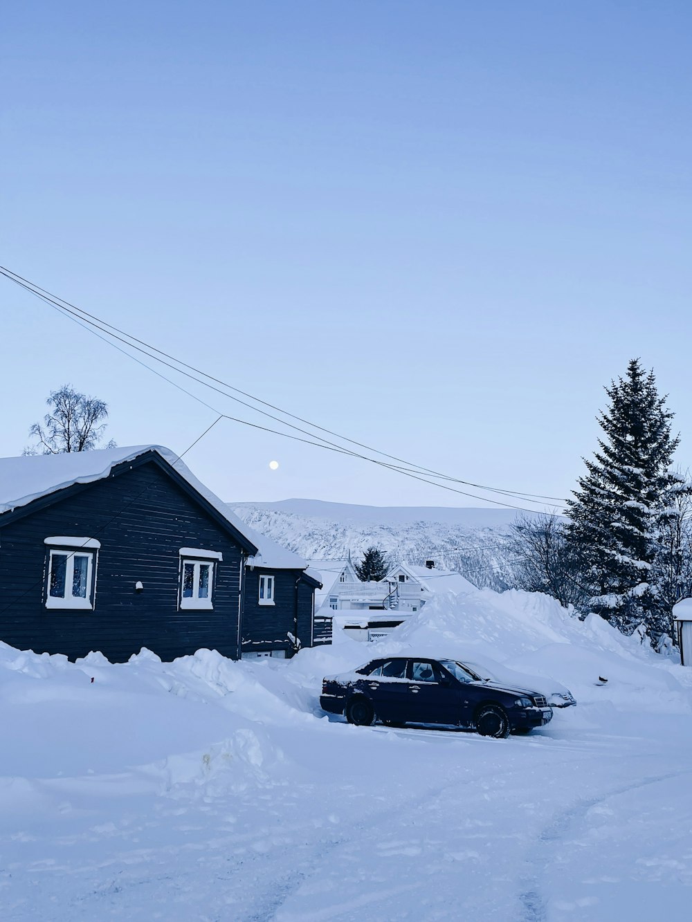 a car is parked in the snow near a house