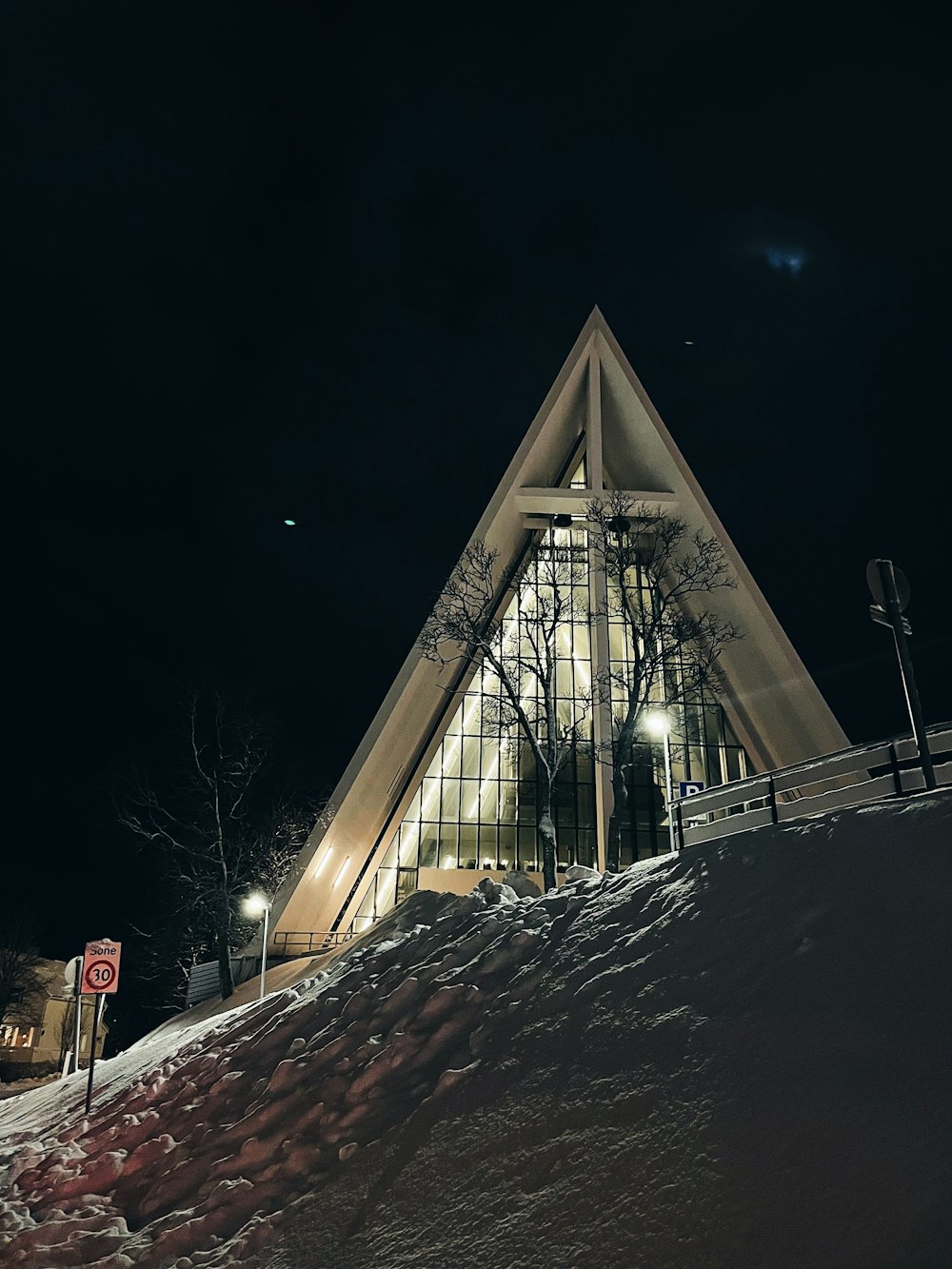 a church with a steeple at night in the snow