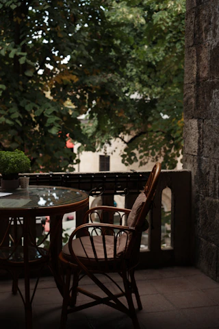 A cozy outdoor patio scene featuring a solid wood leisure chair and a foldable camping table bathed in soft afternoon light.