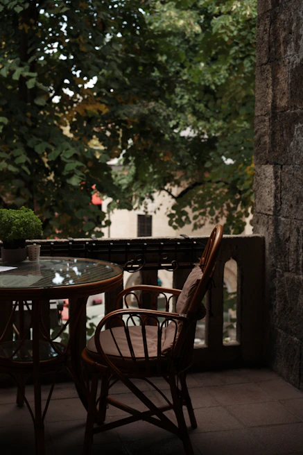 A modern steel patio side table placed beside a cozy lounge chair.