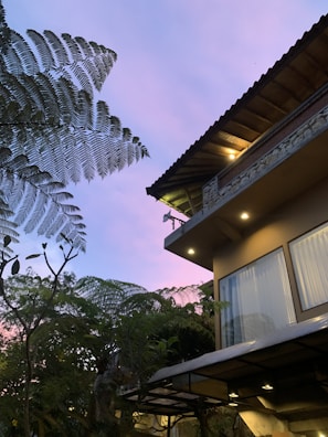 Evening scene of a sleek, modern home with warm interior lights glowing through large windows.