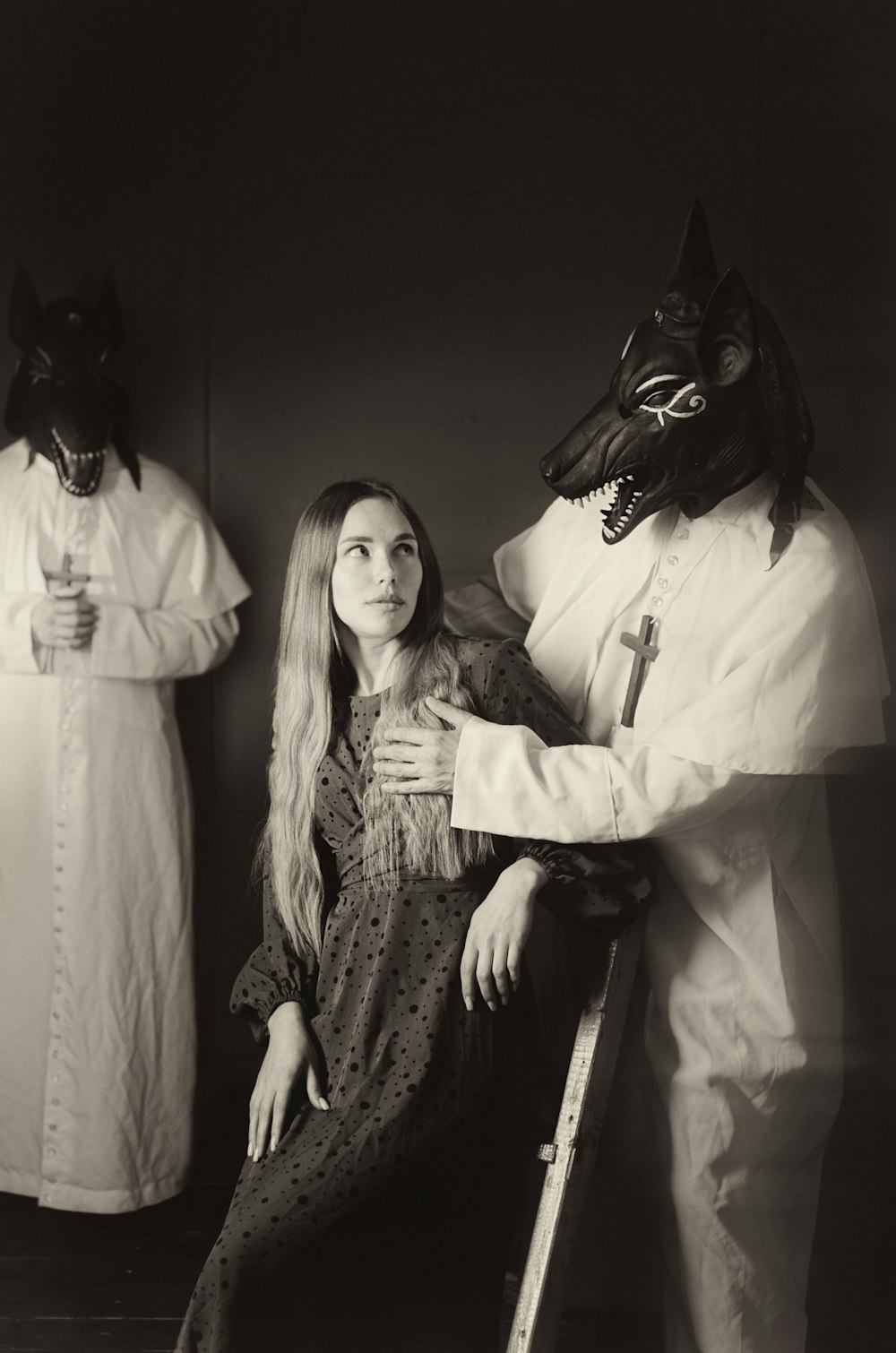 a woman sitting on a chair next to two men in costumes