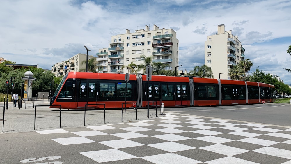 a red and black train traveling past tall buildings