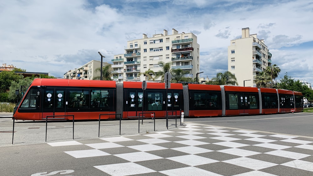 a red and black train traveling past tall buildings