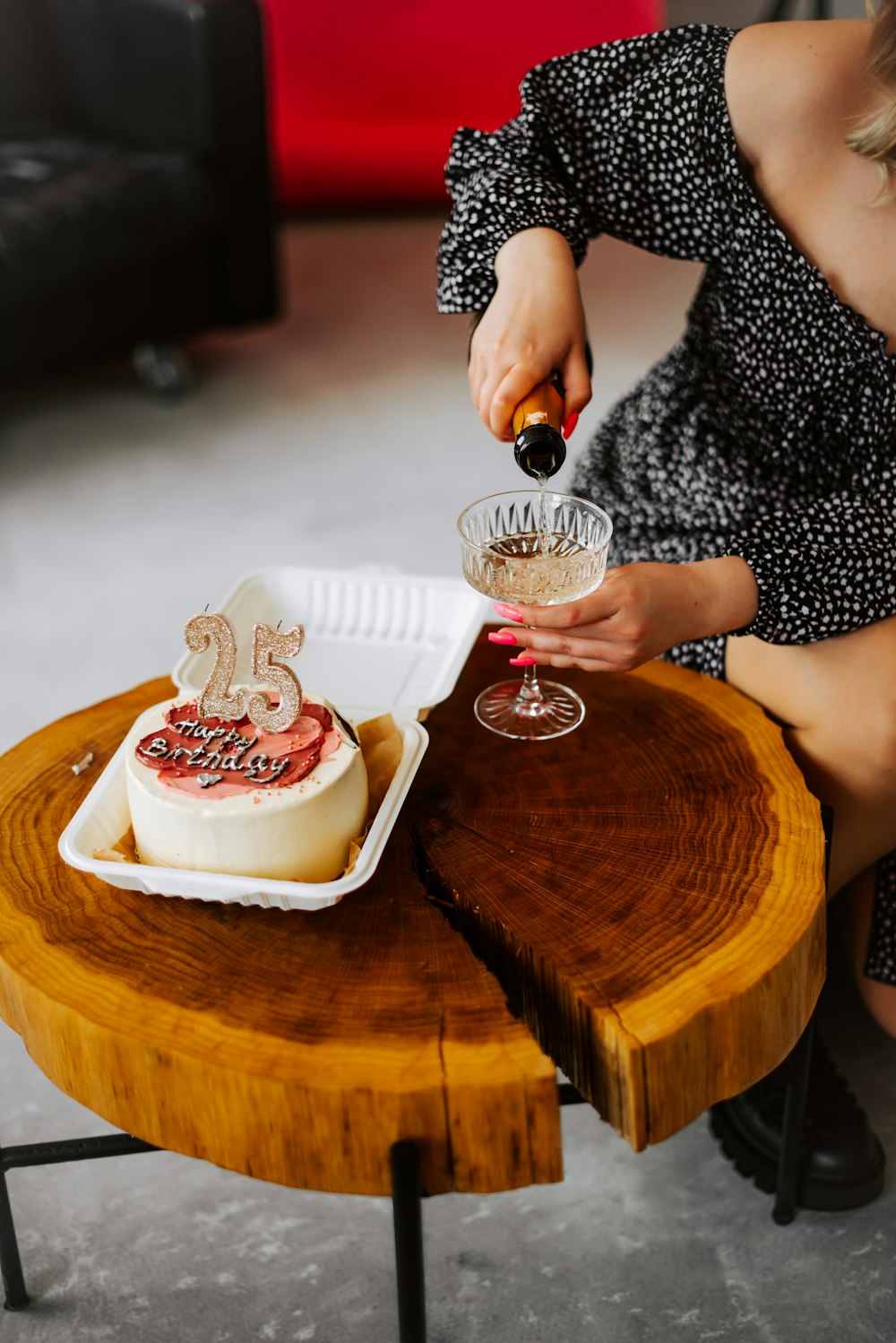 a woman pours a glass of wine in front of a cake