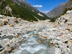 A clear river flowing through a Baja California landscape with mountains in the background.