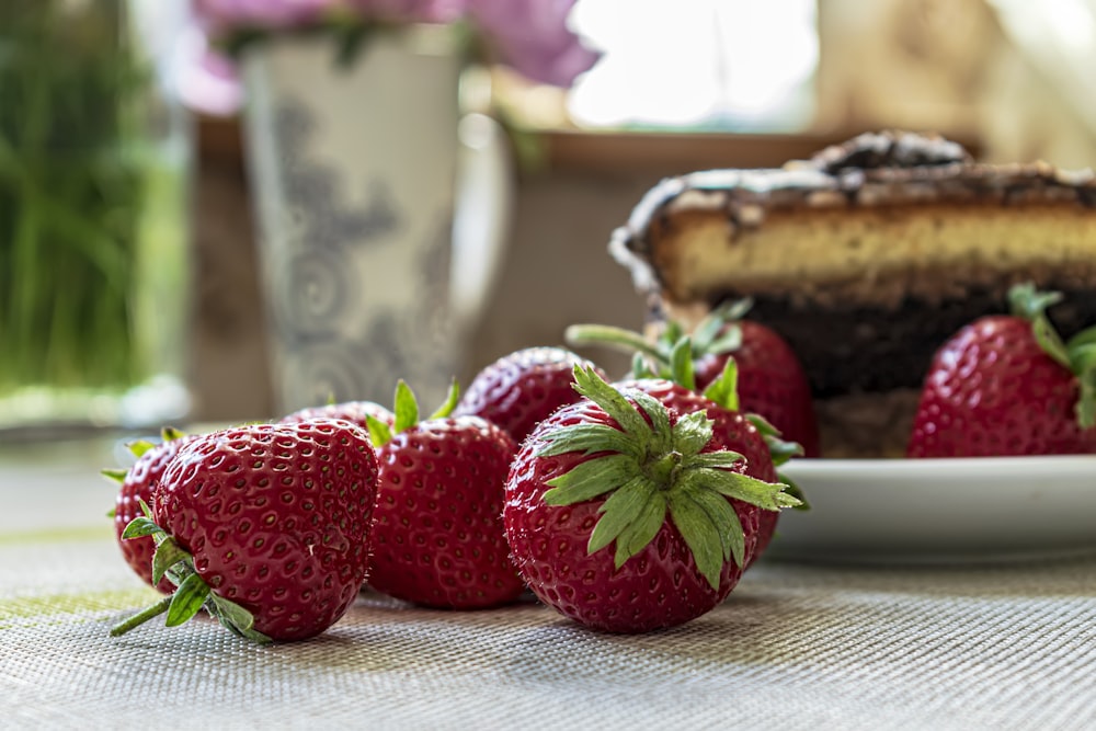 a plate of strawberries next to a slice of cake