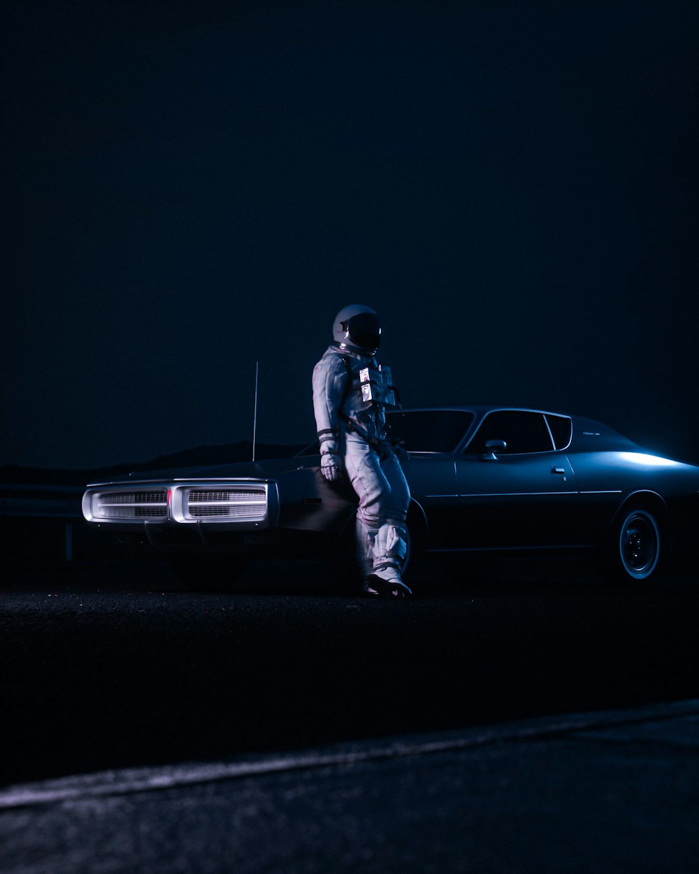 Un hombre parado junto a un coche en la oscuridad