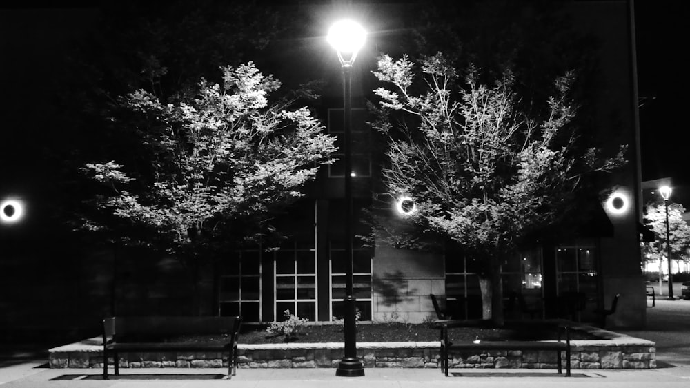 a black and white photo of a park bench at night