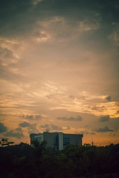 A serene dormitory building surrounded by lush greenery at sunset.