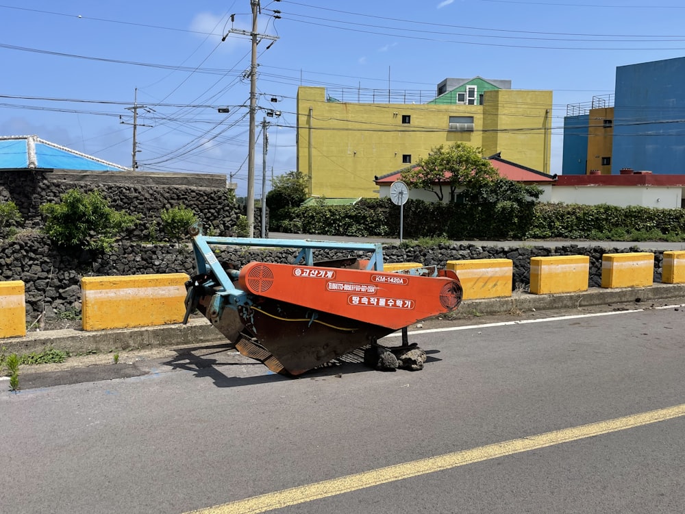 a red boat sitting on the side of a road