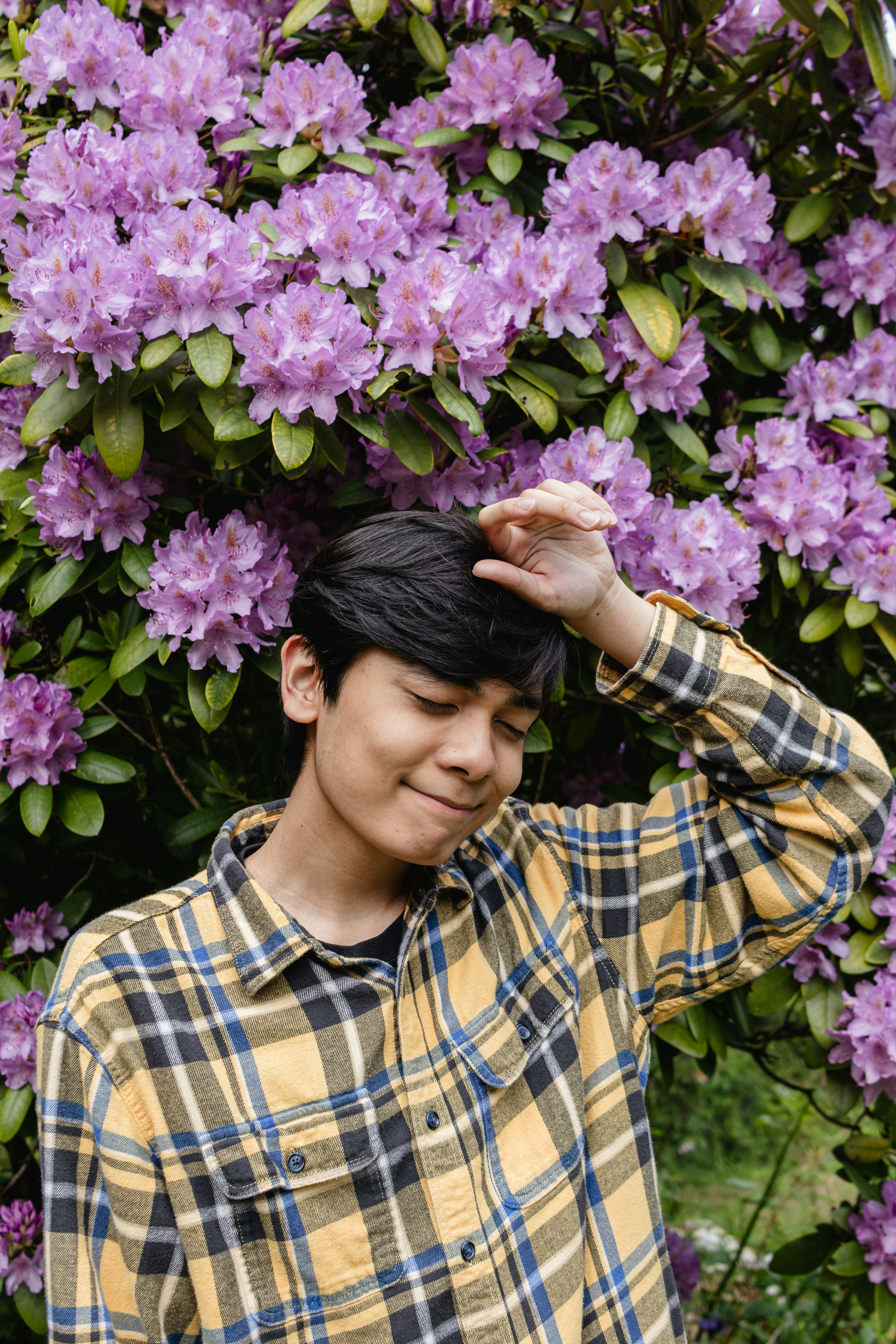a man standing in front of a bush of purple flowers