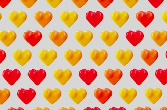 A pattern of heart shapes arranged in rows and columns against a light gray background. The hearts alternate between bright red and a warm golden yellow color, creating a vibrant and repetitive design.