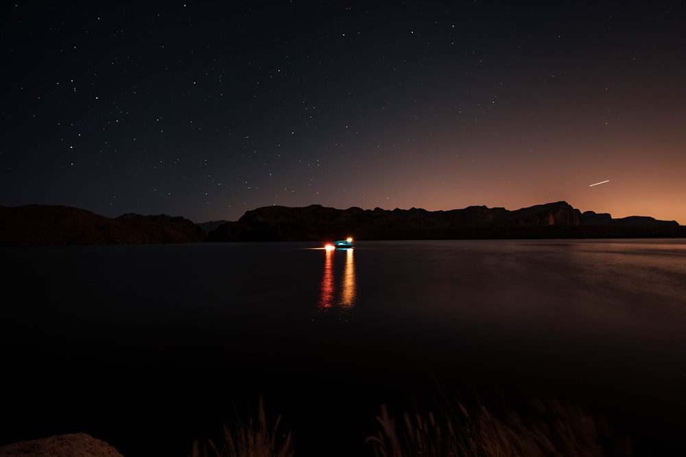 a boat floating on top of a lake under a night sky