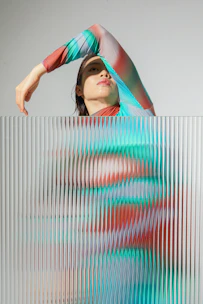 a woman standing behind a wall with her hands on her head