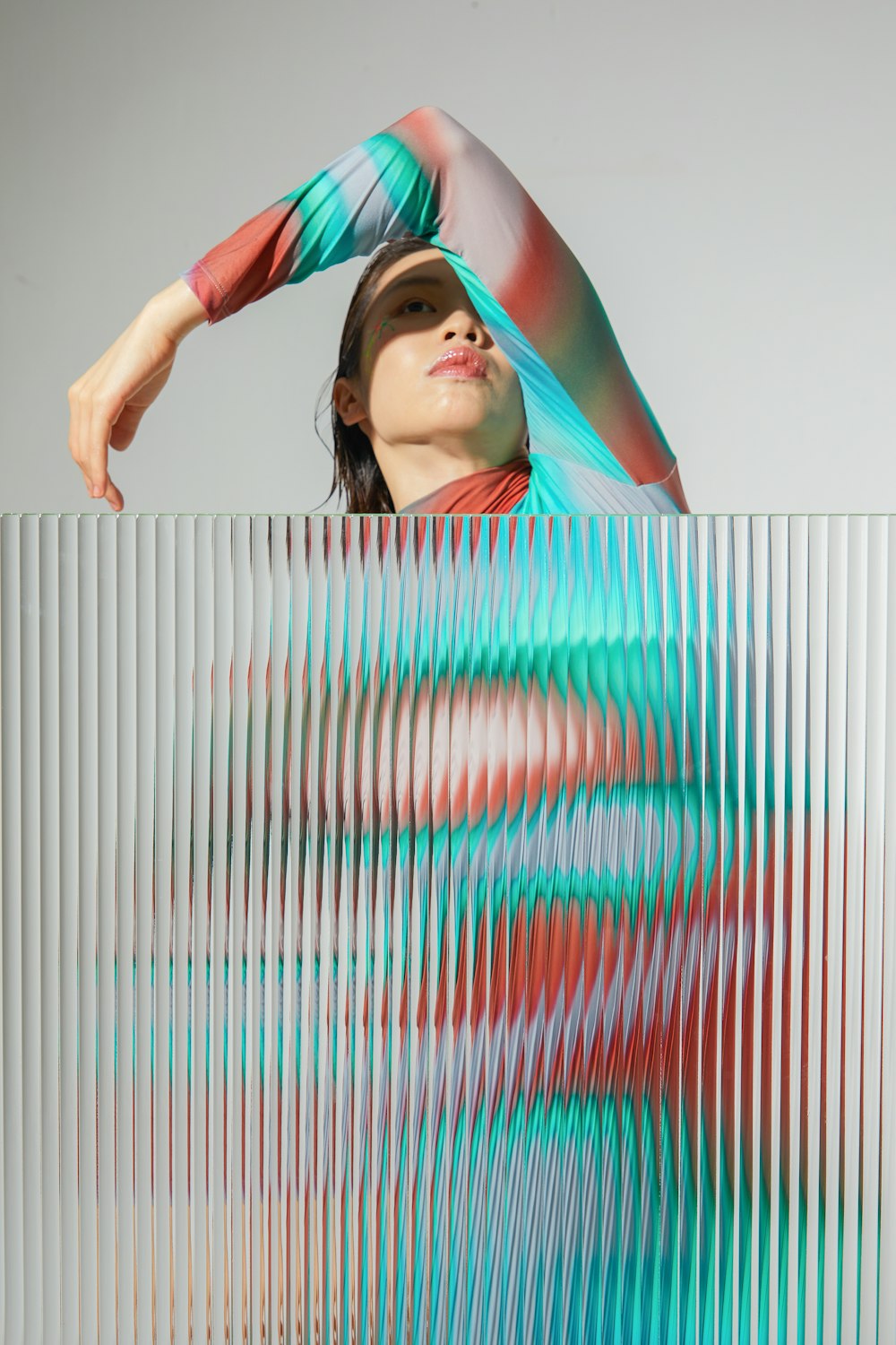 a woman standing behind a wall with her hands on her head