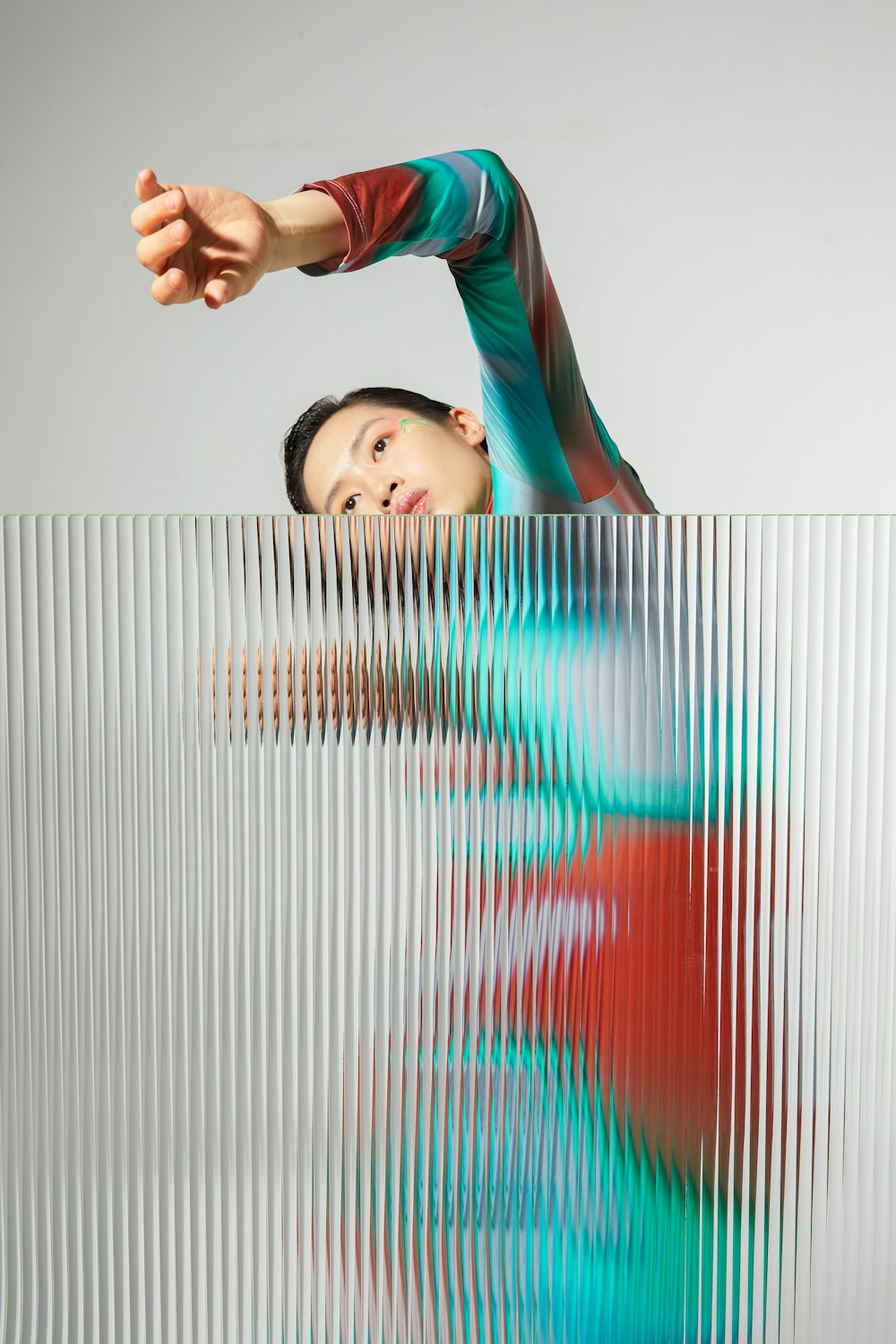 a woman standing behind a wall with her arms stretched out