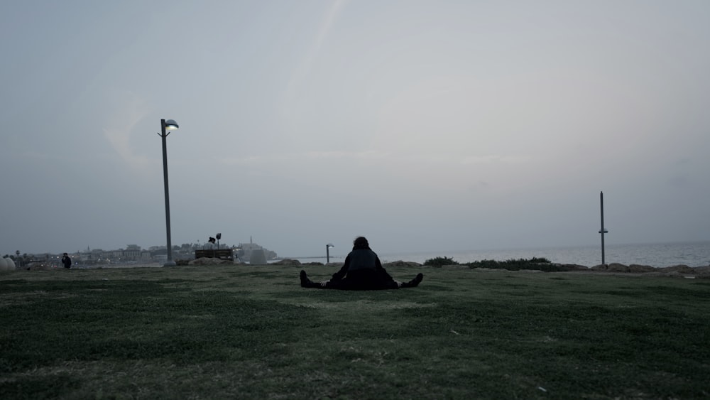 a person sitting on the ground in the grass