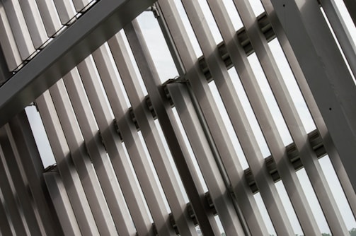 Several metallic slats or panels are aligned in parallel, creating a geometric pattern. The structure is likely part of a modern building facade, emphasizing lines and symmetry.