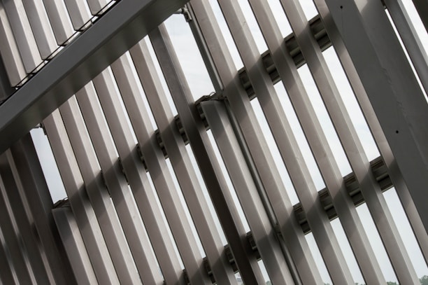 Several metallic slats or panels are aligned in parallel, creating a geometric pattern. The structure is likely part of a modern building facade, emphasizing lines and symmetry.